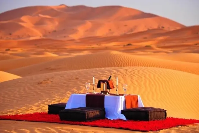 A romantic dinner set in the Sahara Desert, featuring a beautifully arranged table under a starry sky morocco desert