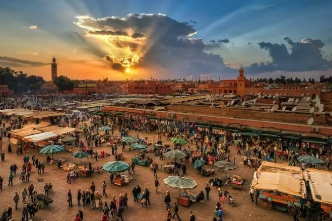 Sunset casting warm hues over the bustling market in Marrakech, highlighting vibrant stalls and lively atmosphere Marrakech Tours