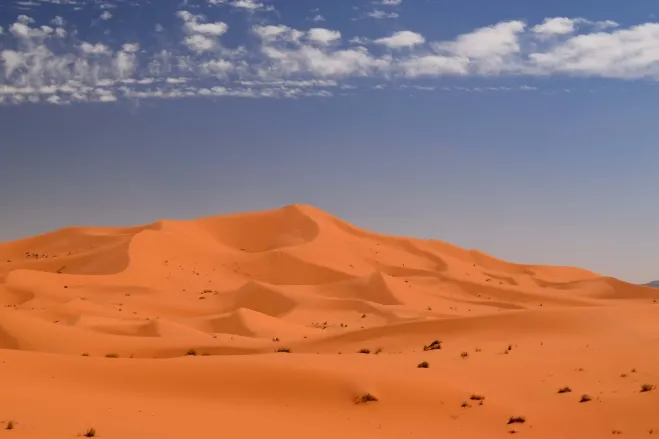 Sahara Desert landscape in Morocco, showcasing vast sand dunes under a clear blue sky 