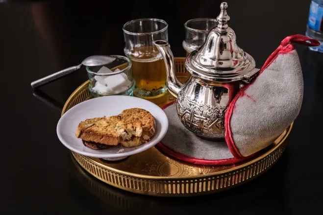 A tray elegantly arranged with a teapot, cups, and an assortment of cookies morocco tour