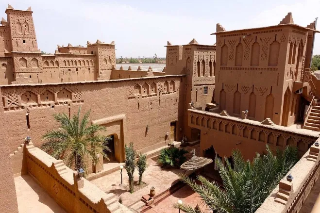 A serene courtyard of an ancient building surrounded by arid desert landscape under a clear blue sky morocco desert