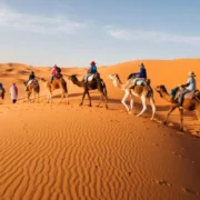 A table and chairs arranged in the desert, illuminated by the warm hues of a stunning sunset morocco desert tour