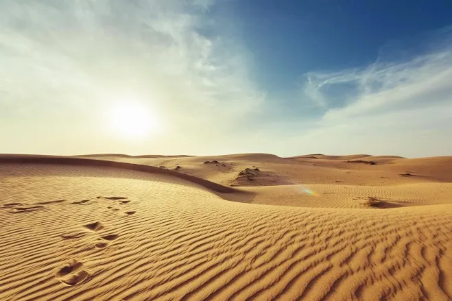 Footprints in the golden sand of the Sahara Desert, illustrating a solitary journey across the vast, arid landscape Erg Chebbi Dunes