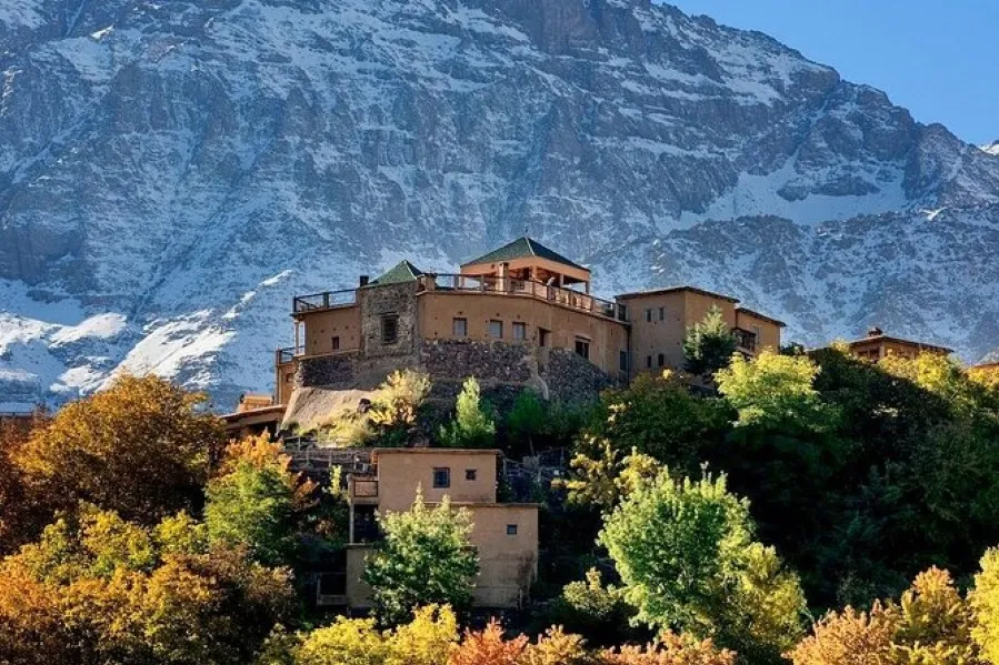 A picturesque mountain village in Morocco, featuring traditional Berber architecture with a castle looming in the background.