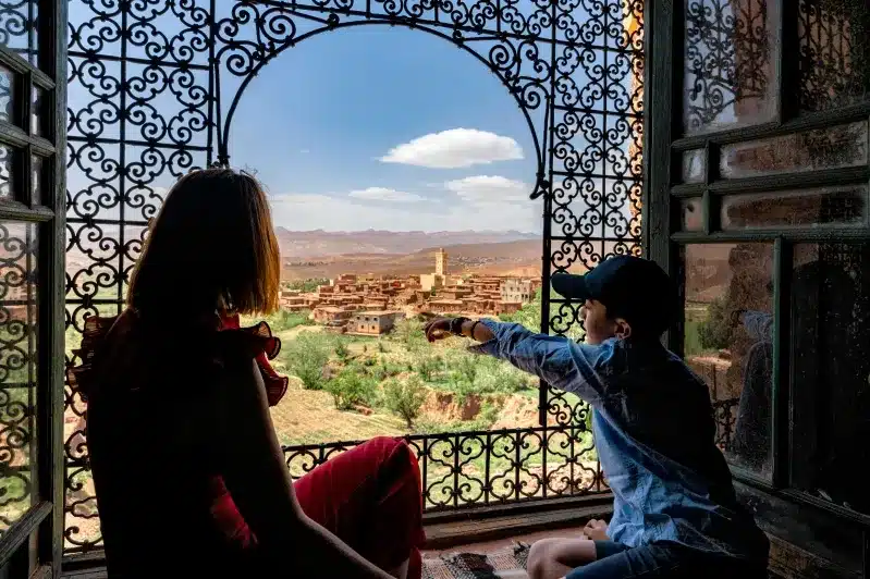 A woman and child gaze out a window, admiring the scenic view during their Morocco family tours.