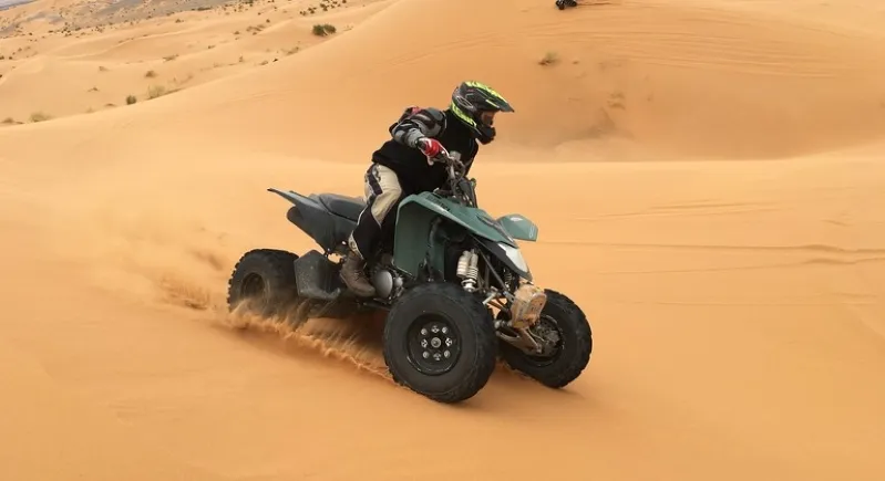 An individual navigating an ATV across the vast desert terrain in Morocco, highlighting the excitement of Quad Biking in Morocco.