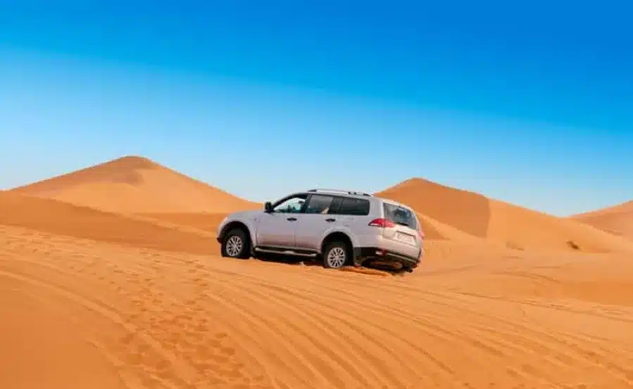 A white SUV navigates the vast desert landscape of Morocco, showcasing the adventure of a private driving experience.