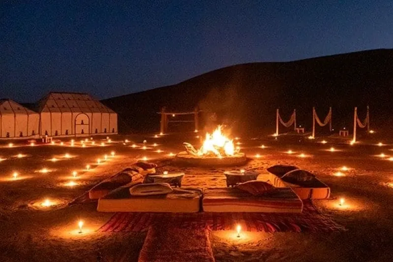 A cozy fire pit set in the Sahara desert, featuring a tent and a bed, perfect for a luxury tour experience from Marrakech.