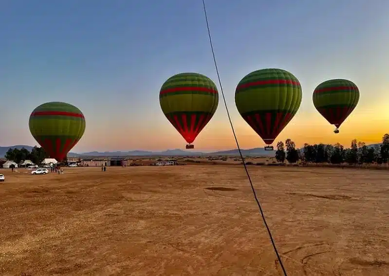 A stunning sunset sky filled with hot air balloons, highlighting the picturesque views of Morocco with a private driver.