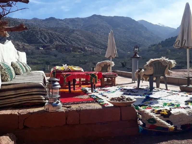 A cozy patio featuring a rug and chairs, set against the stunning backdrop of the Berber Villages in Morocco's mountains.