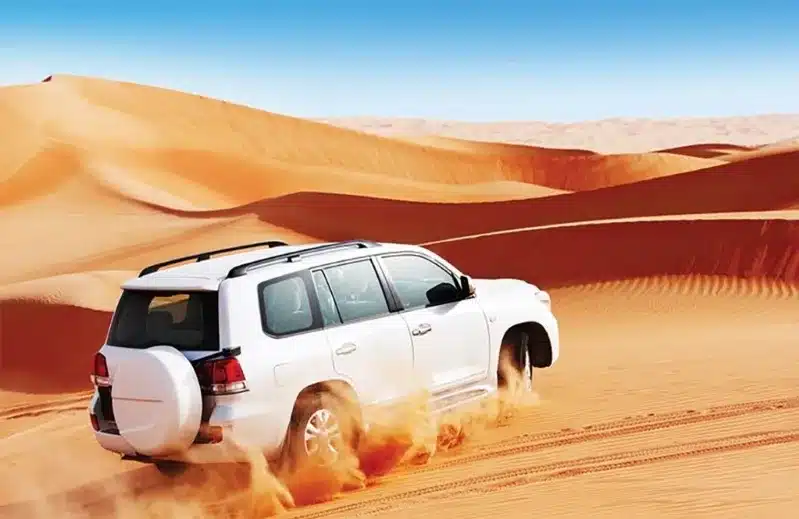 A white SUV traverses the arid desert terrain in Morocco, highlighting the thrill of a Morocco private driver journey.