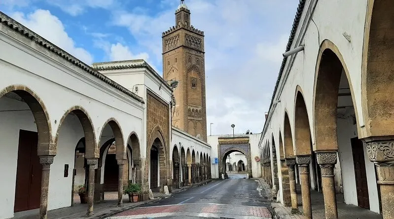 A narrow alley in Casablanca featuring arches and a clock tower, perfect for casablanca sightseeing and exploring the city's architecture.
