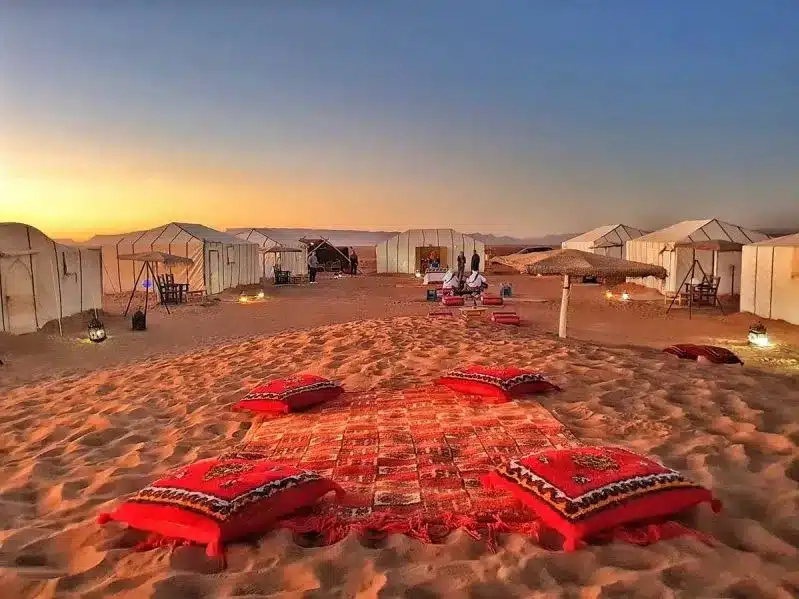 Tents and vibrant pillows set against the backdrop of a tranquil morocco desert excursion.