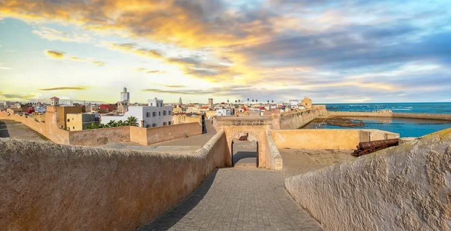 A stunning sunset casts vibrant hues over the cityscape of Marrakech, Morocco, highlighting its unique architecture.