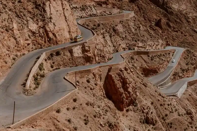 A car navigates a winding mountain road during a scenic road trip in Morocco, showcasing stunning landscapes.