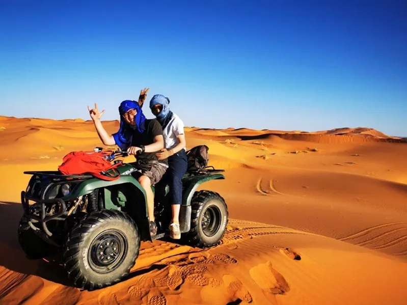 Two individuals riding an ATV through the vast expanse of the Moroccan desert during an adventurous excursion.