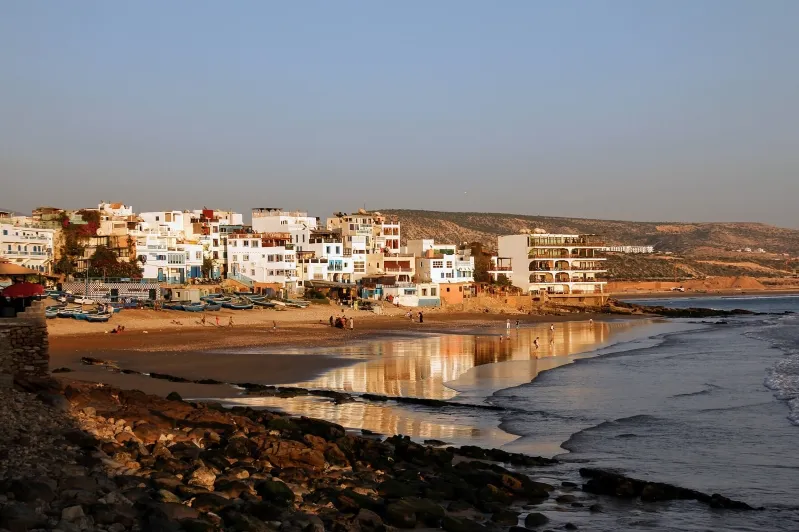 A picturesque Moroccan beach scene with various buildings along the coastline, ideal for beach holidays.