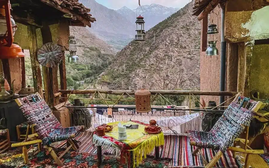 A table and chairs on a balcony with a stunning mountain view, perfect for relaxation during a 7-day Morocco tour.