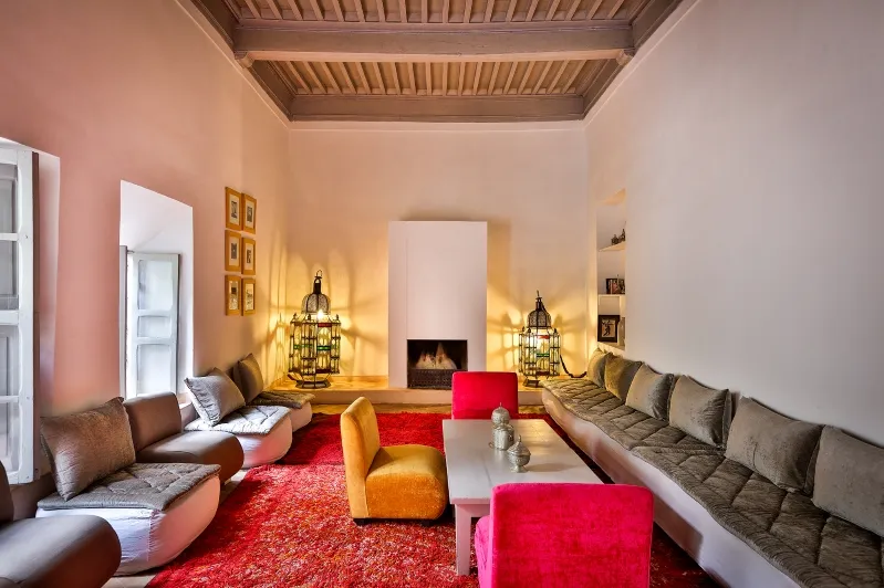A cozy living room featuring a fireplace and vibrant couches, perfect for relaxation after gueliz marrakesch shopping. 