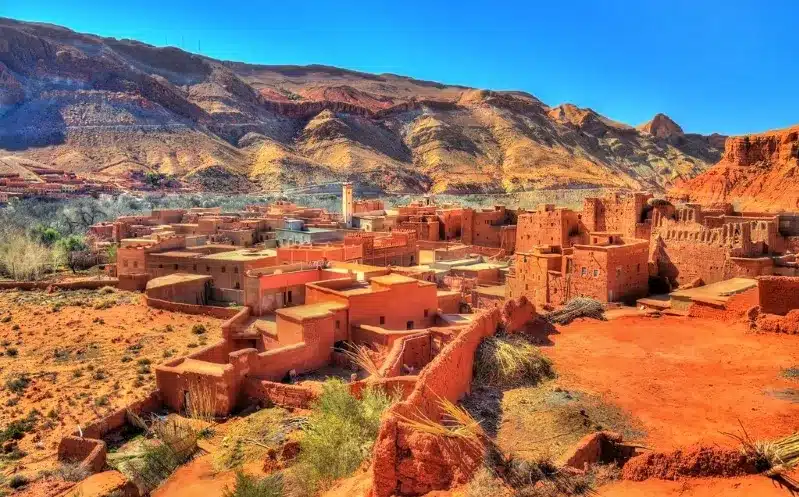The village of Atlas in the Moroccan desert, featuring traditional structures against a backdrop of vast sandy terrain.