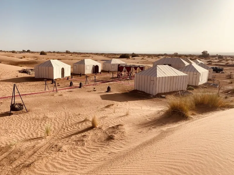 A scenic view of tents in the desert, with rolling sand dunes, showcasing the allure of Morocco's camel tours.