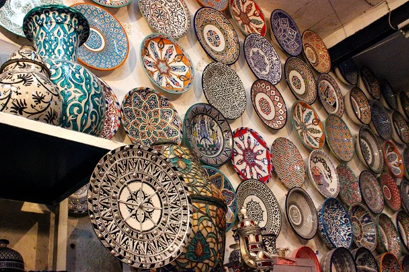 A decorative wall adorned with various plates and vases, showcasing the artistry of Marrakech travel service. 