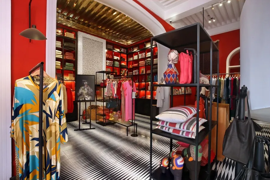 A designer clothing store in Marrakech featuring striking red walls and a black and white striped floor.