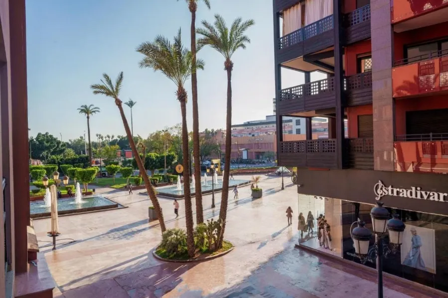 A scenic view from a balcony in Gueliz, Marrakech, showcasing vibrant shops and the lively atmosphere of the city.