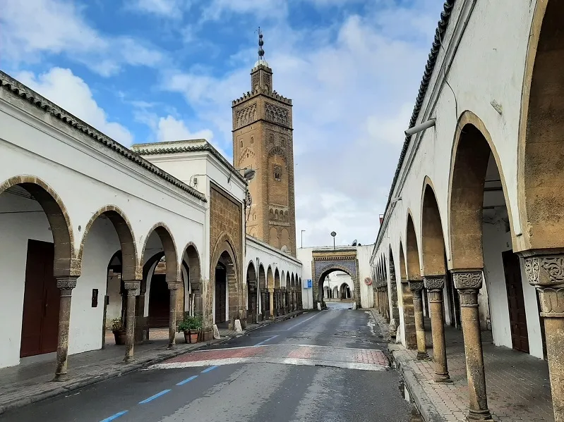 A picturesque street in Casablanca featuring a prominent clock tower and elegant arches, showcasing the city's charm.with Casablanca Tourist Places