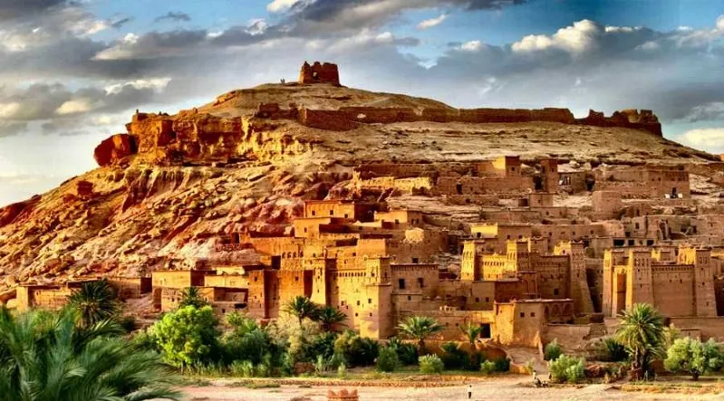 Four individuals riding camels across a vast desert landscape during a two-day tour from Marrakech to Merzouga.