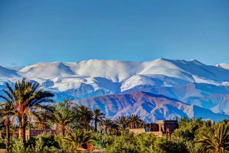 Snow-capped High Atlas Mountains in Morocco, showcasing majestic peaks against a clear blue sky.