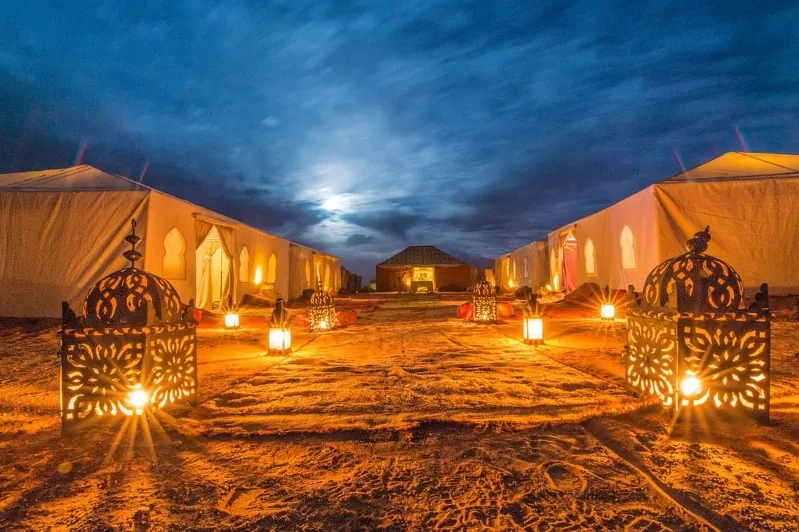 The moon illuminates tents in the desert, creating a serene atmosphere for travelers enjoying Jet2 holidays to Marrakech.