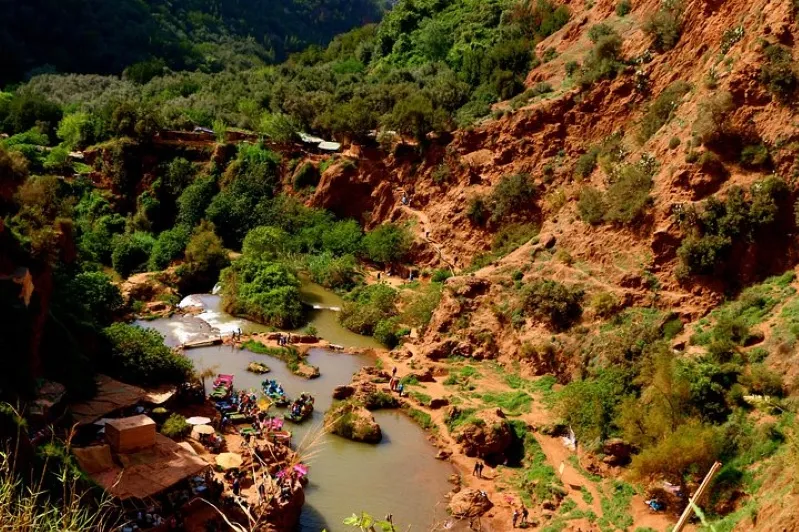 A river flows through a majestic canyon surrounded by mountains near the stunning Ouzoud Waterfalls.