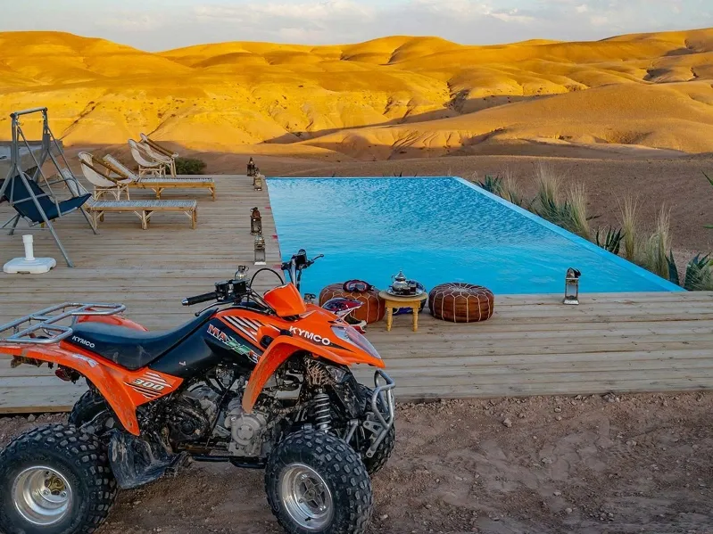 A quad bike parked beside a pool in the Agafay Desert, Morocco, showcasing the arid landscape and leisure setting.