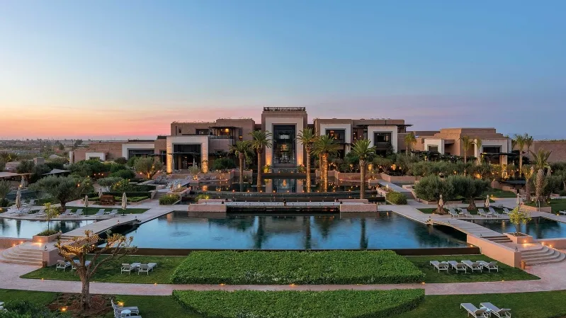 The resort in Marrakech, Morocco, bathed in the warm hues of sunset, offering a picturesque view for an all-inclusive trip.