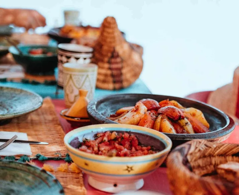  A table adorned with an array of Moroccan dishes, featuring numerous plates of food and colorful bowls.