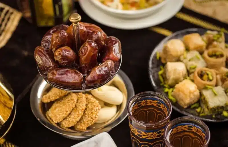 A table adorned with Arabic food, featuring dates and halwa chebakia, showcasing a rich cultural culinary experience.
