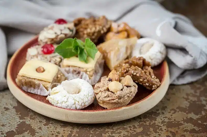 A plate filled with an assortment of traditional Moroccan sweets, showcasing vibrant colors and intricate designs.
