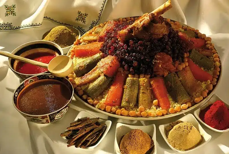 A plate filled with a colorful dish accompanied by various bowls of spices arranged around it.