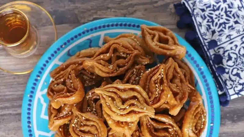 A plate of traditional Moroccan sweets accompanied by a cup of tea on a beautifully set table.