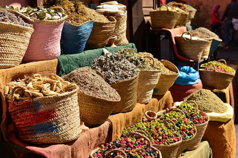 Baskets overflowing with colorful herbs and spices on a table, representing the rich flavors of authentic Moroccan food.