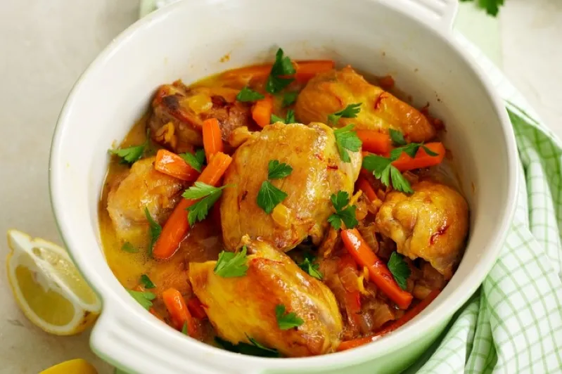 A white dish featuring chicken, carrots, and parsley, beautifully arranged for a delightful meal.