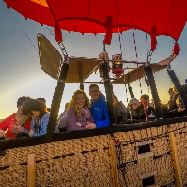 A group of people enjoying a scenic view while sitting in a colorful hot air balloon.