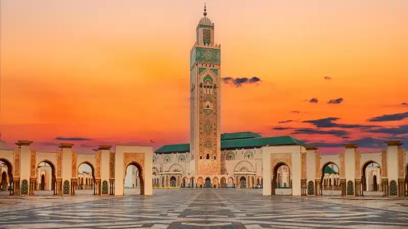 Islamic mosque in Morocco silhouetted against a vibrant sunset, best time to visit morocco. 