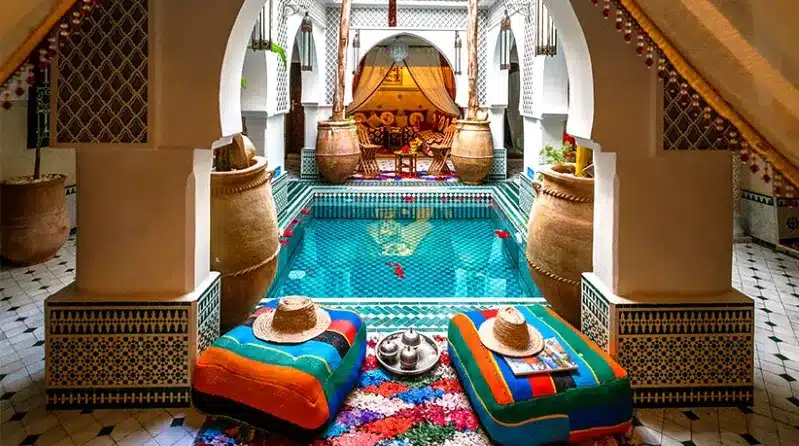 A lively pool surrounded by colorful pillows and a large rug, illustrating the essence of Moroccan cost of living.