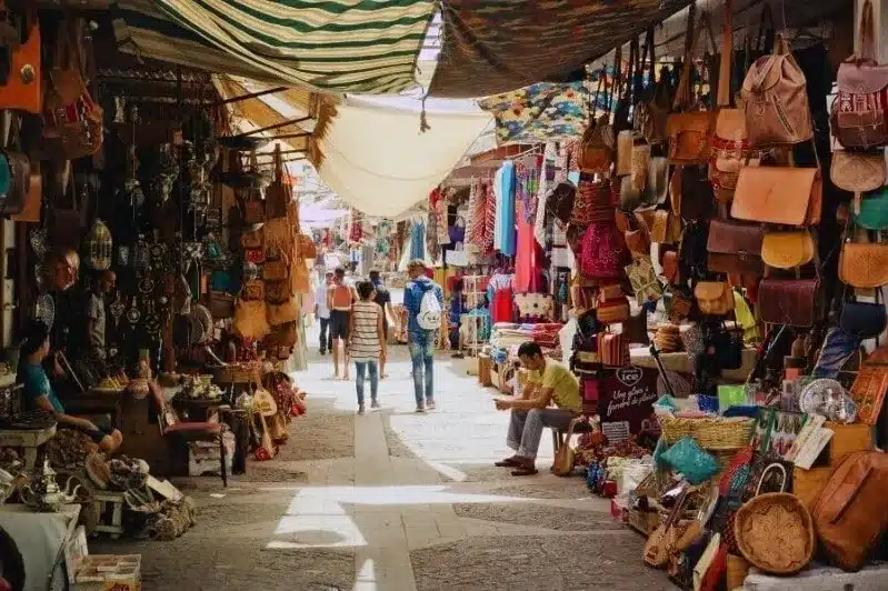 A bustling Moroccan market showcasing a variety of bags and purses, highlighting local craftsmanship and Morocco Cost of Living. 