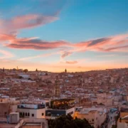 Sunset over Marrakech, Morocco, casting vibrant colors across the city skyline and illuminating the surrounding landscape.