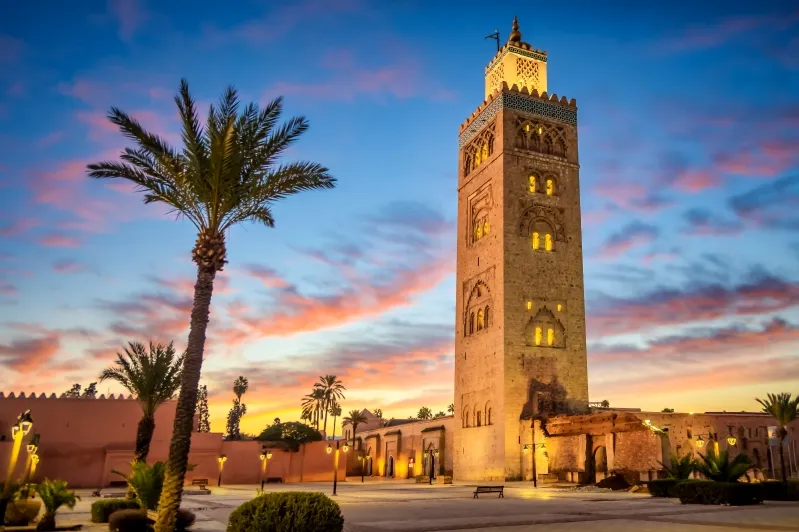 Clock tower of a mosque in Morocco, showcasing intricate architecture against a clear blue sky. 