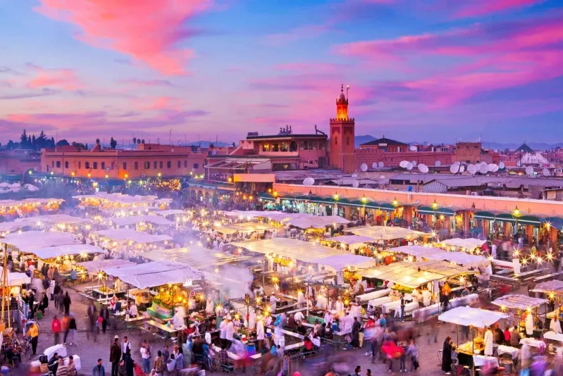 Marrakech skyline at dusk, showcasing vibrant colors and city lights, perfect for an all-inclusive Morocco vacation.