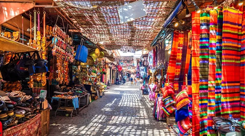A narrow Moroccan alley adorned with vibrant cloths and various items, showcasing local culture and craftsmanship.